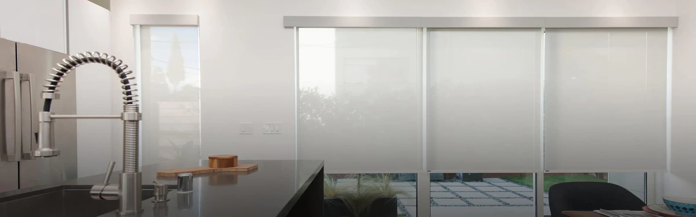Translucent solar shades reducing glare across a modern kitchen window wall