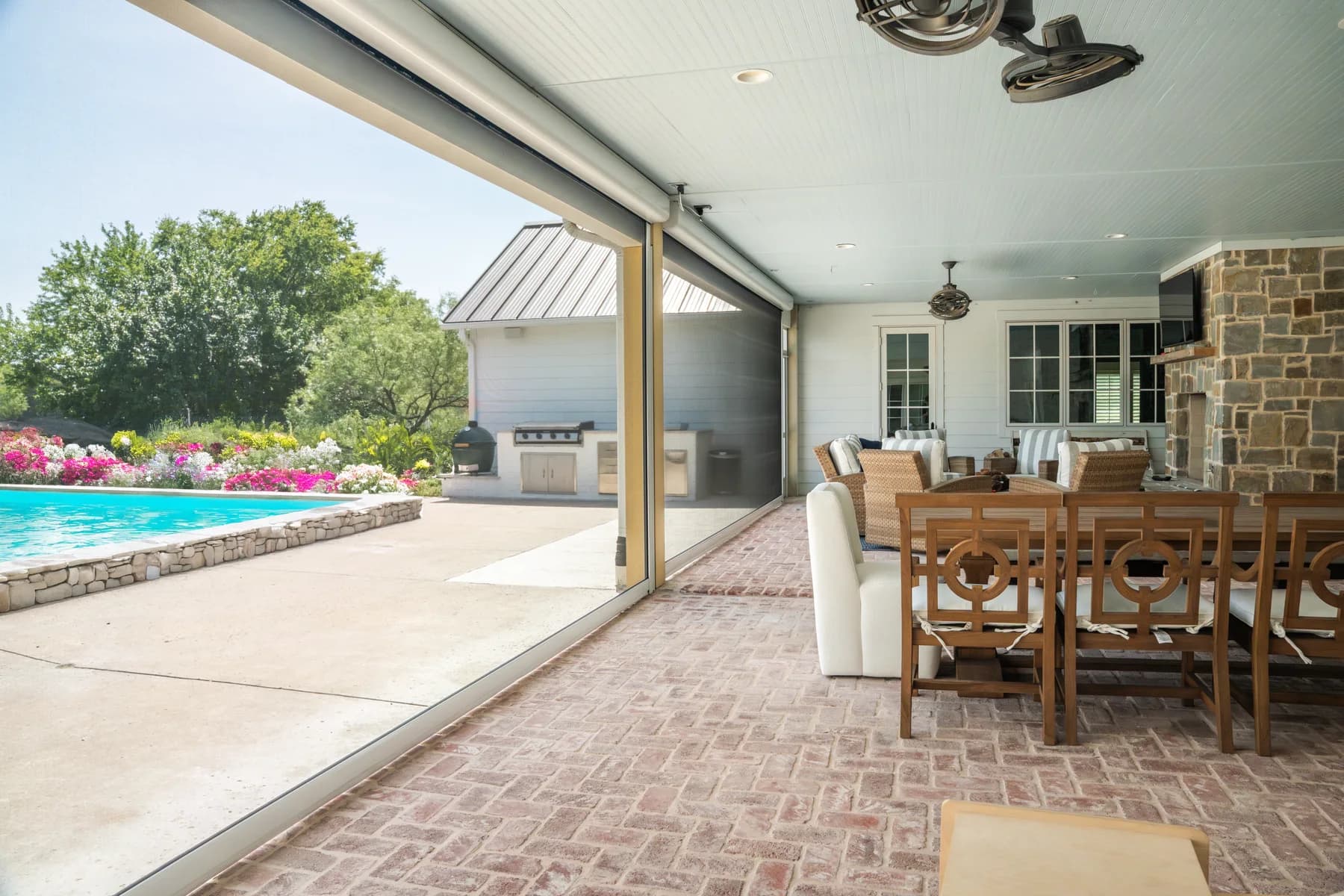 Motorized exterior screens enclosing a furnished covered patio beside a pool