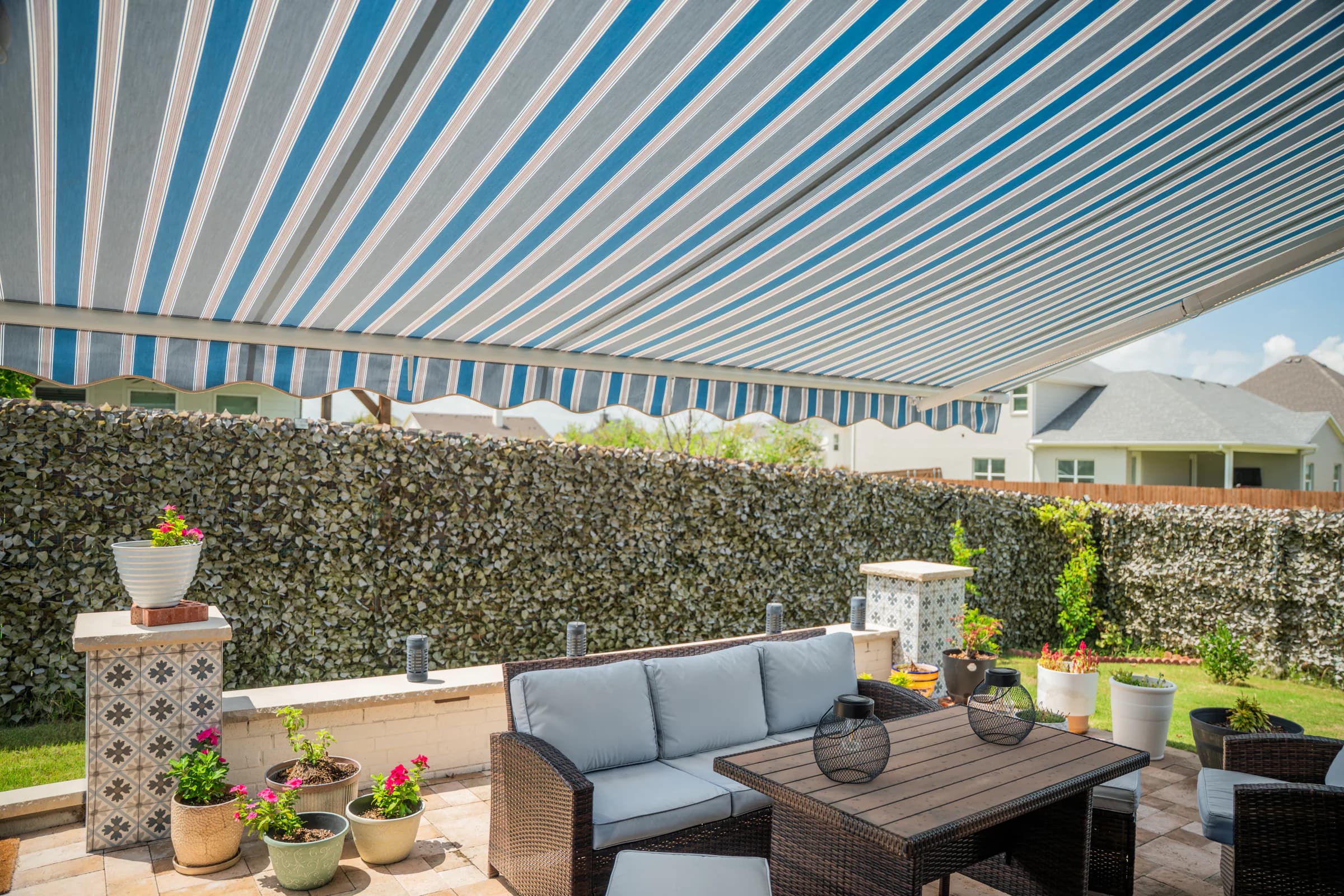 A striped exterior awning shading a furnished garden patio